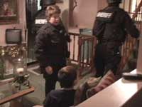 Picture of a living room where a child is sitting on the couch with Police and SWAT in the room.